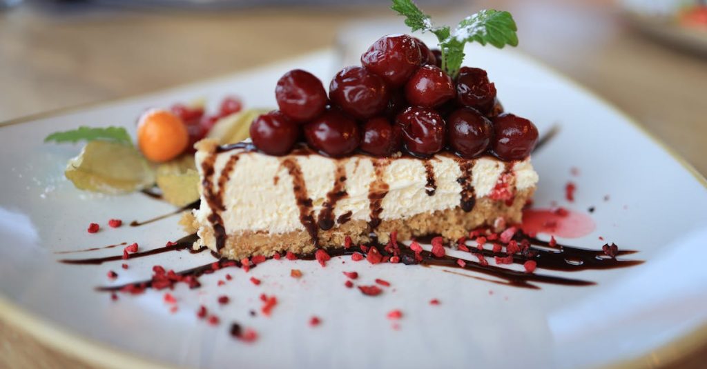 Close-up of a delectable cherry-topped cheesecake slice with chocolate drizzle on a ceramic plate.