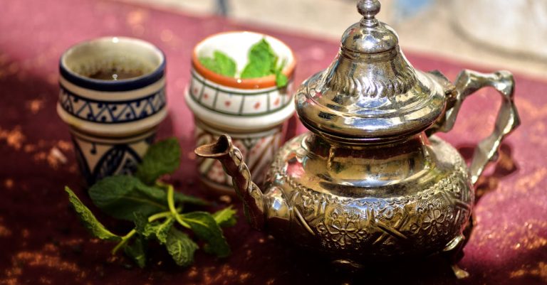 A traditional Moroccan mint tea set with a silver teapot and cups outdoors in Fès, Morocco.