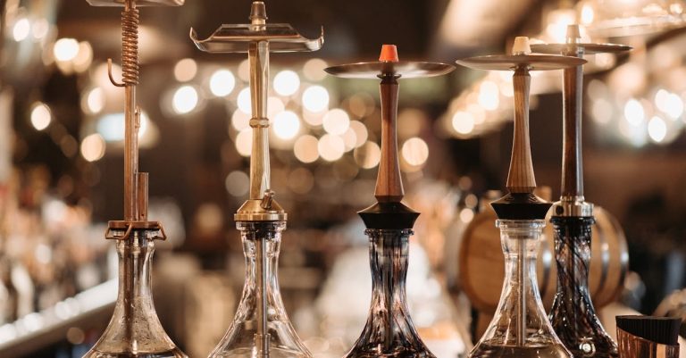 A collection of elegant hookahs displayed on a bar counter, accented by warm bokeh lights.