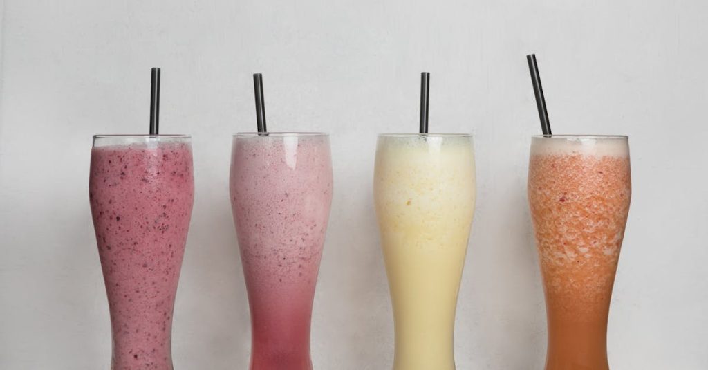 Four refreshing tropical shakes in tall glasses with straws, perfect for summer.